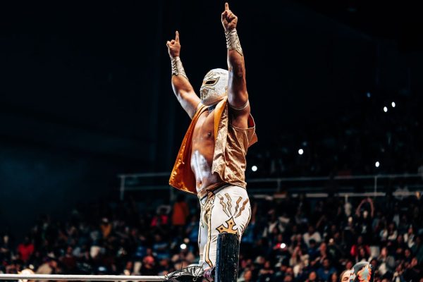 WWE摔角擂台全景，四角绳围起的摔角场在聚光灯下闪耀，观众席座无虚席，橙色与白色灯光交织